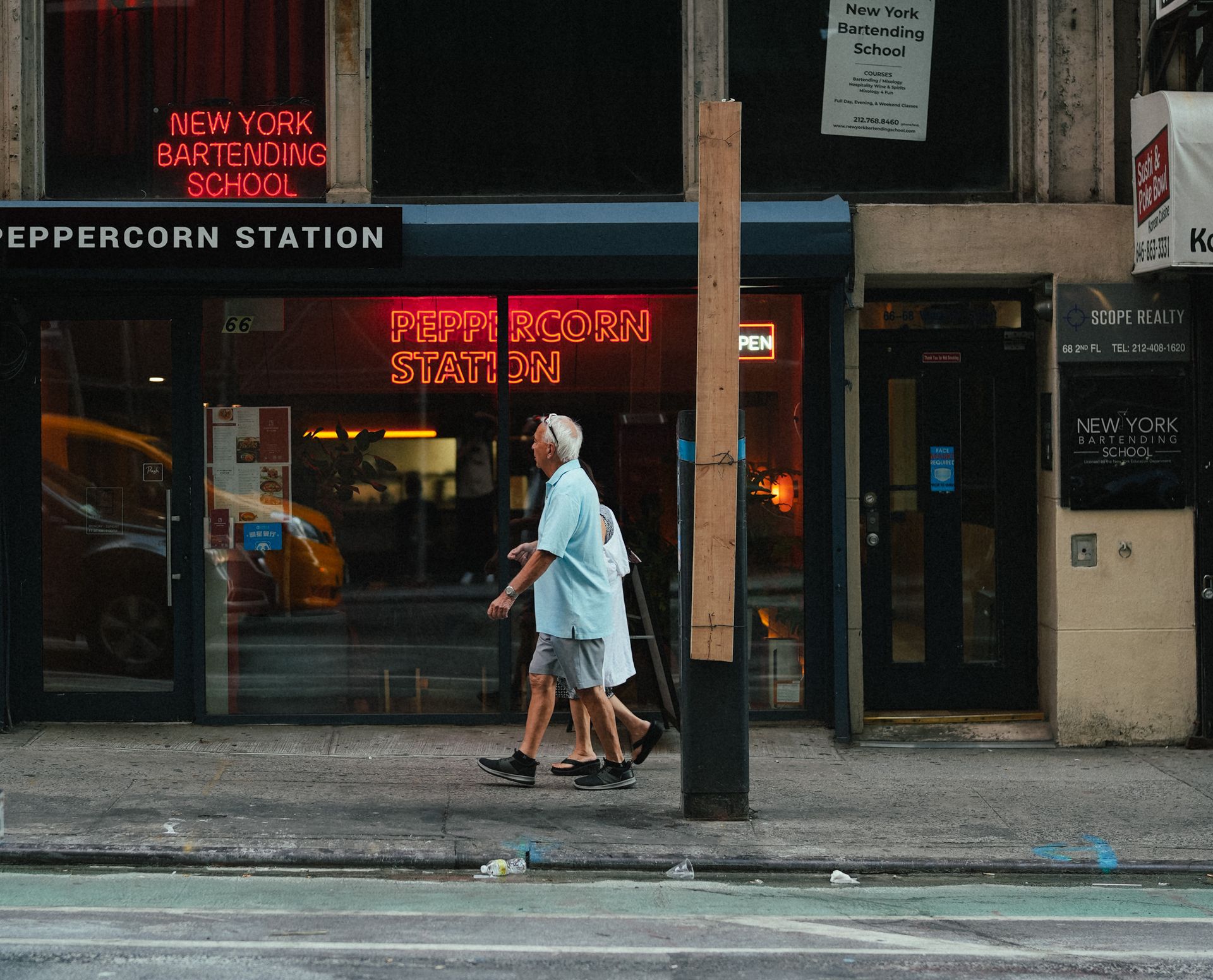 Elderly couple walking past a restaurant on a New York City street, enjoying a casual day outdoors.