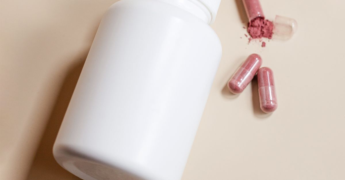 Close-up of a white pill bottle without a label and capsules lying next to it