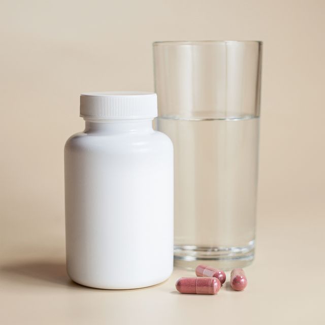 Health supplement bottle beside a glass of water