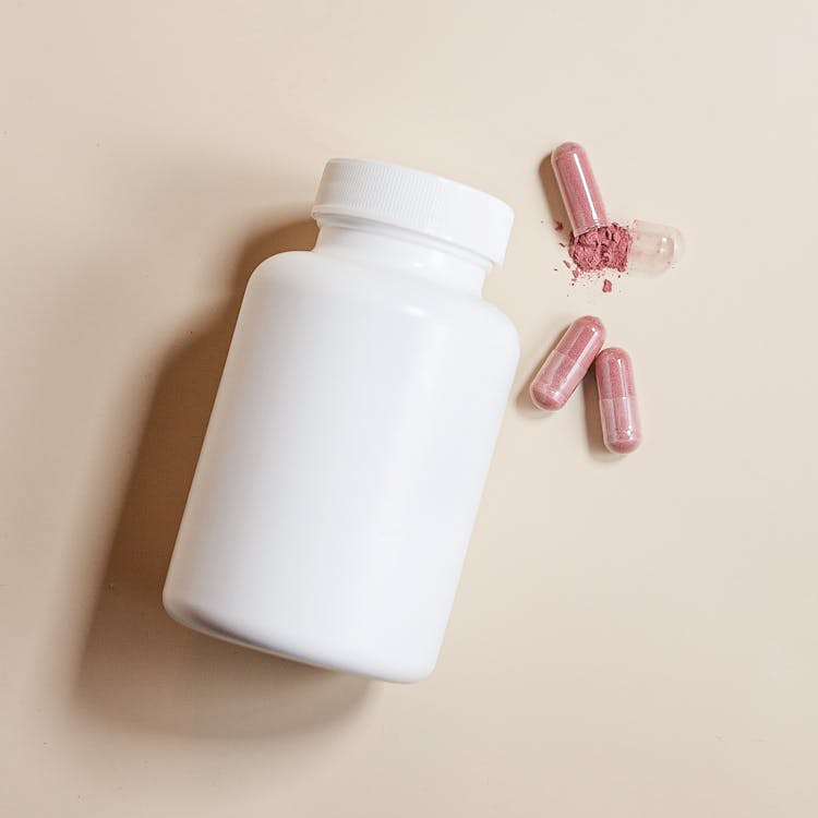 Capsules Beside A White Container 