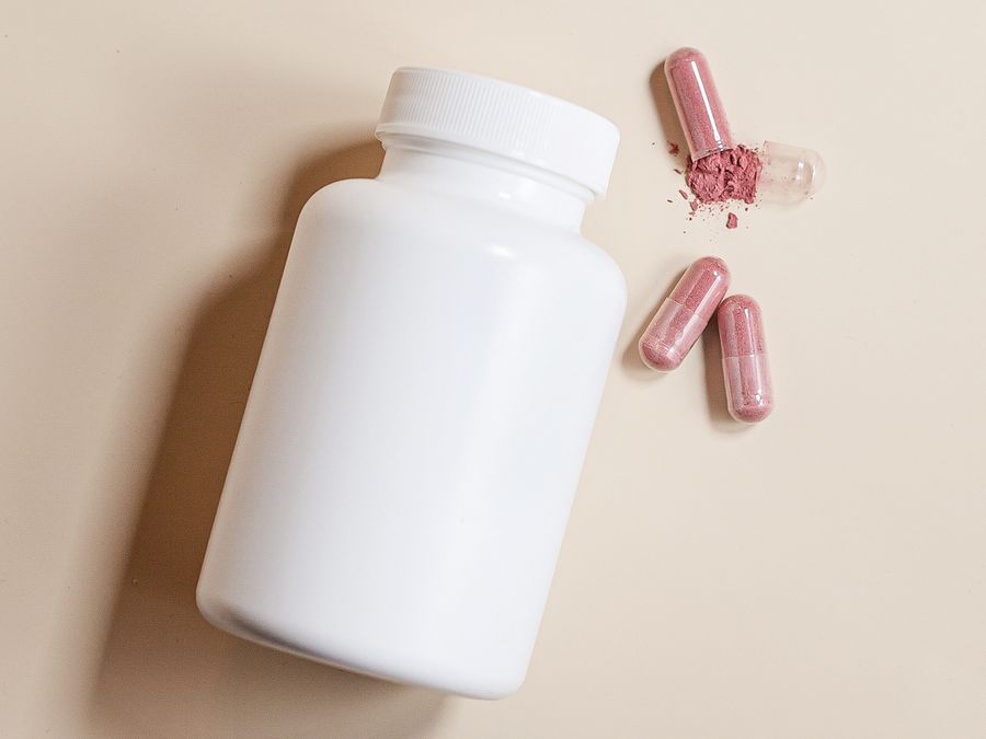 Supplement bottle and capsules on a cream background