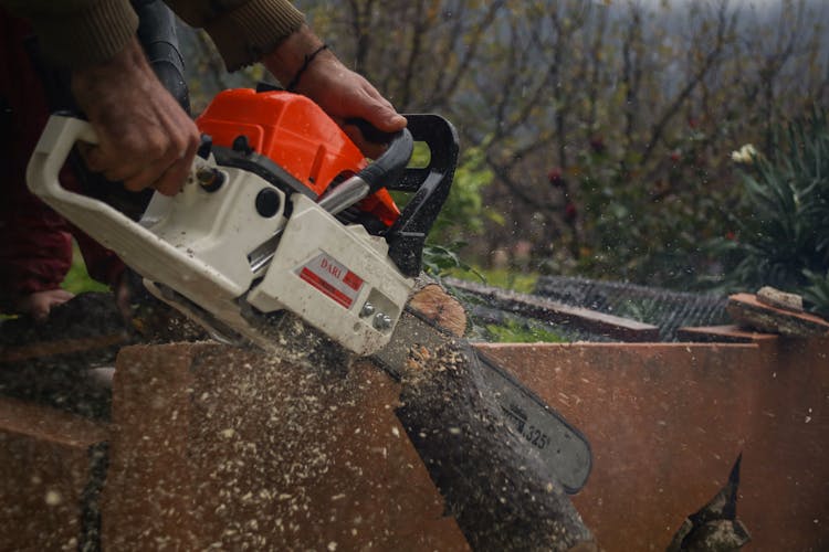 A Man Cutting A Wood Using Chainsaw