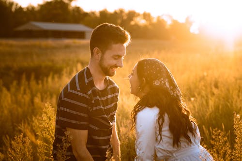 A Couple Looking at Each Other while Standing on the Field