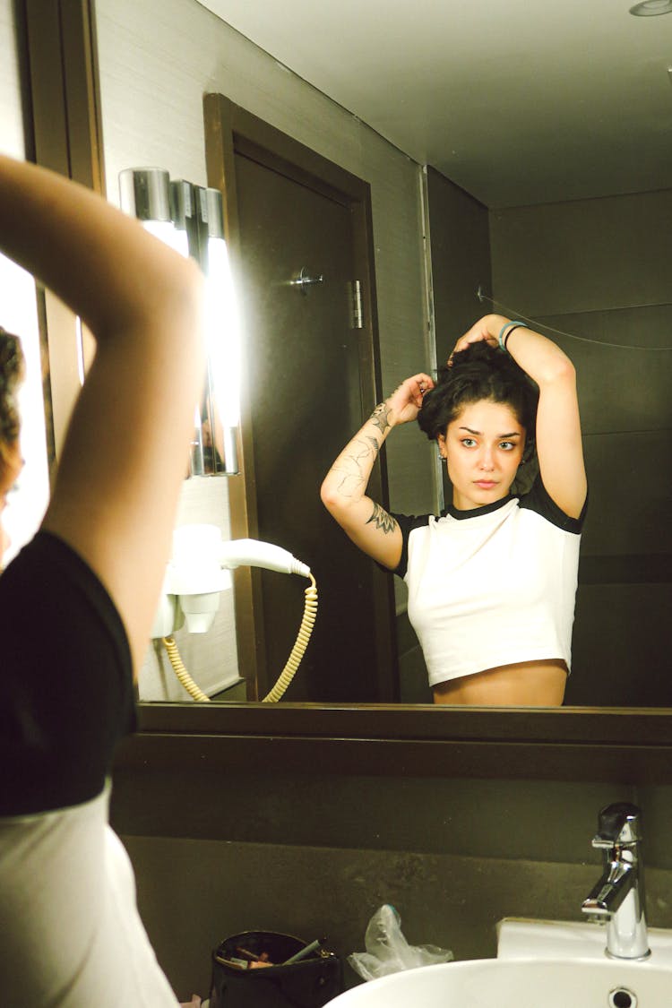 Woman Fixing Her Hair In Mirror