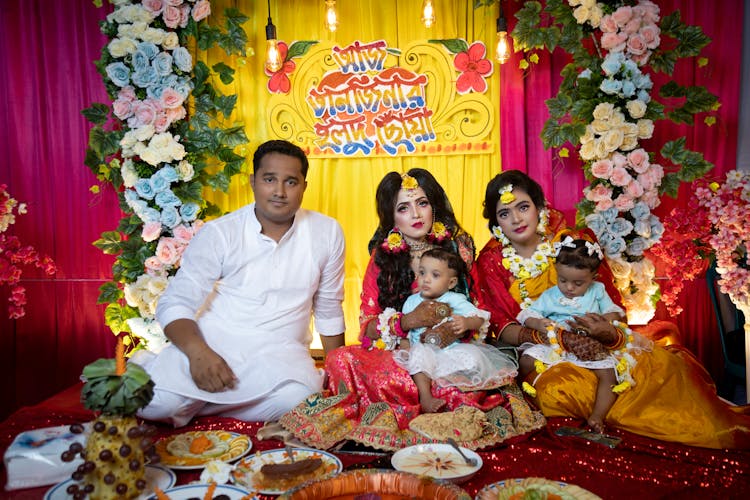 Women Holding Babies And Man Sitting In Front Of Meal