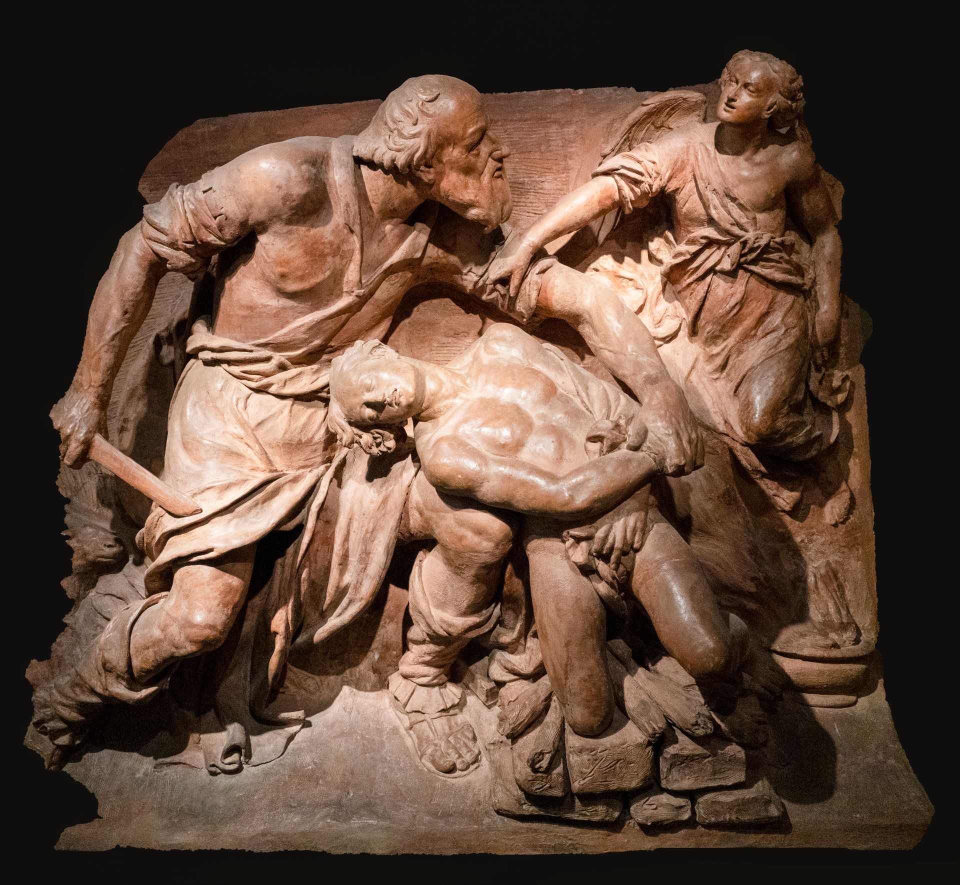 A detailed relief sculpture depicting a dramatic scene of three human figures in dynamic poses.
