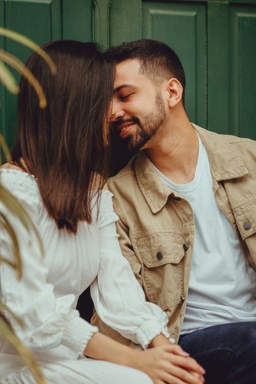 Free A couple embracing lovingly against a green door, exuding romance and warmth. Stock Photo