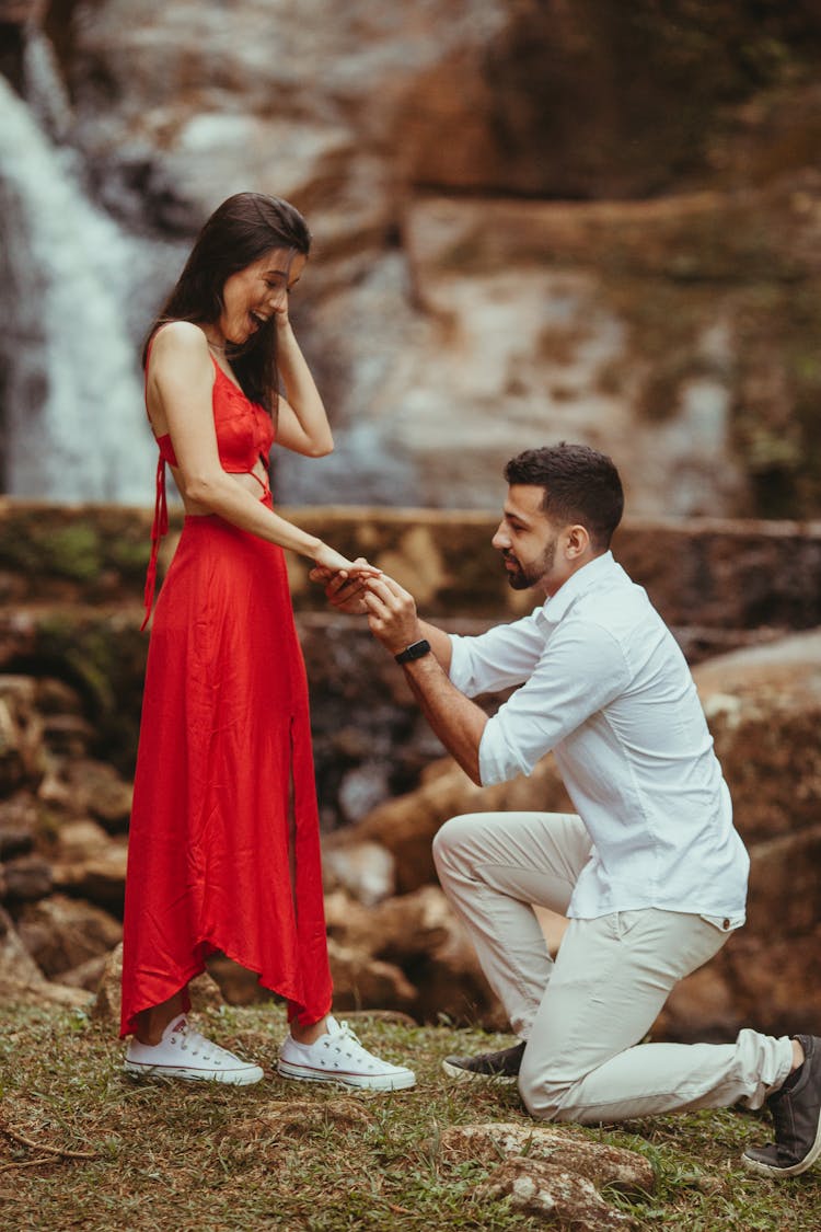 Man Kneeling In Front Of A Woman In Red Dress