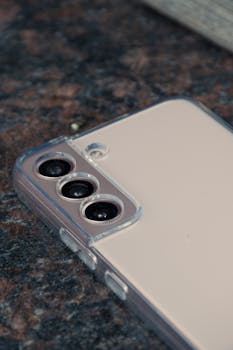 Detailed close-up of a modern smartphone triple camera on a marble surface.