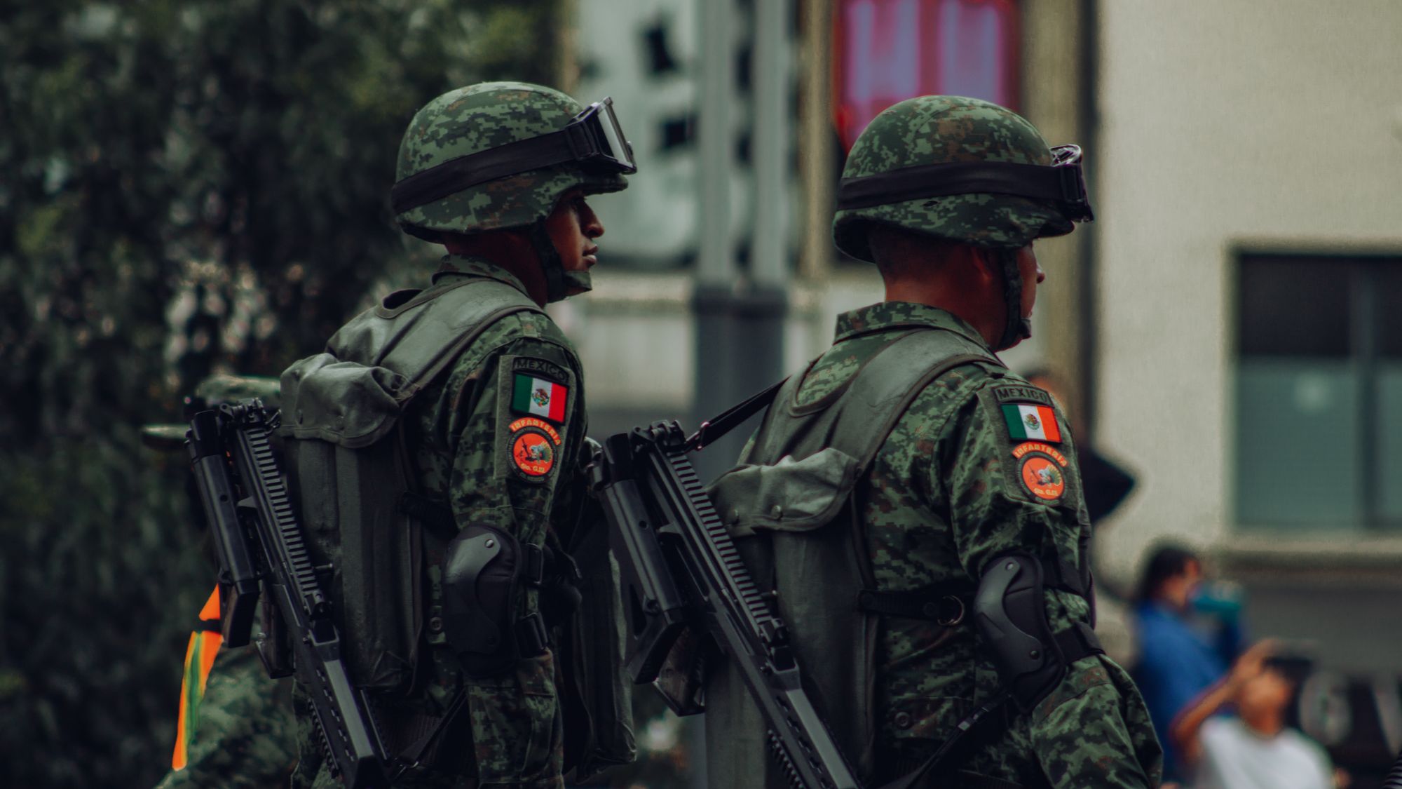Militares mexicanos con equipo táctico patrullan una calle urbana desde la caja de una camioneta