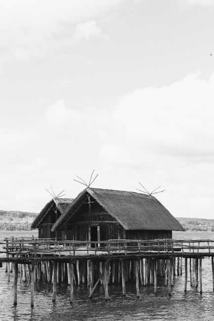 Grayscale image of traditional wooden stilt houses over a lake, evoking history.
