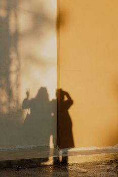 Shadow of people on a two-tone wall at sunset, creating an artistic urban ambiance.