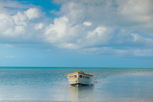 Free Tranquil scene with a boat on the ocean, blue sky, and fluffy clouds, capturing peaceful nature. Stock Photo