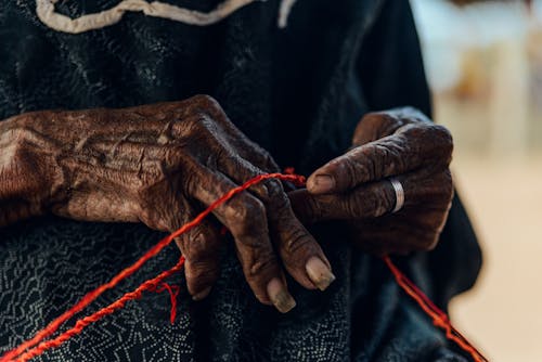 Close-up of Old Woman Hands with Red Thread