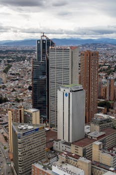 Aerial shot of Bogotá showcasing tall high-rise buildings under a cloudy sky.