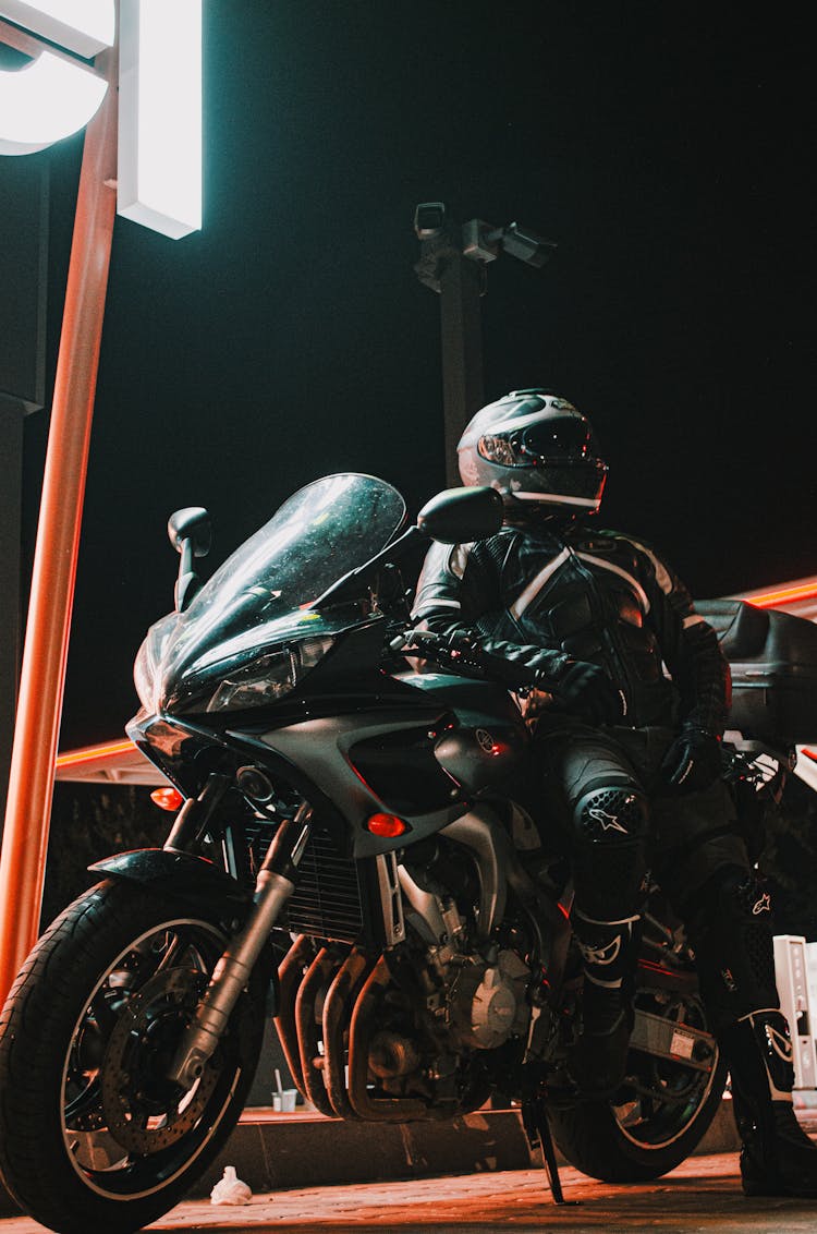 Person In A Helmet Leaning On A Black Motorcycle