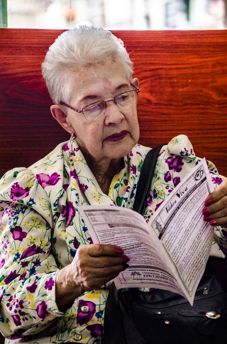 An Elderly Woman Reading A Pamphlet