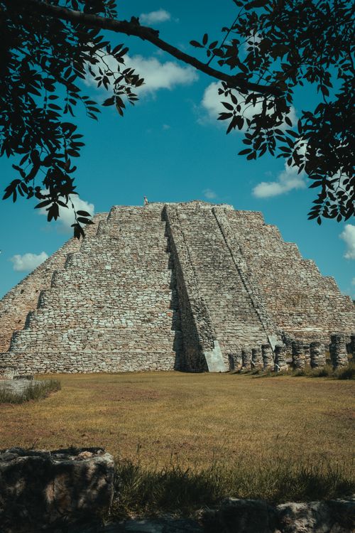Free Explore the ancient Mayapan pyramid in Yucatan, Mexico under a clear blue sky framed by leafy branches. Stock Photo