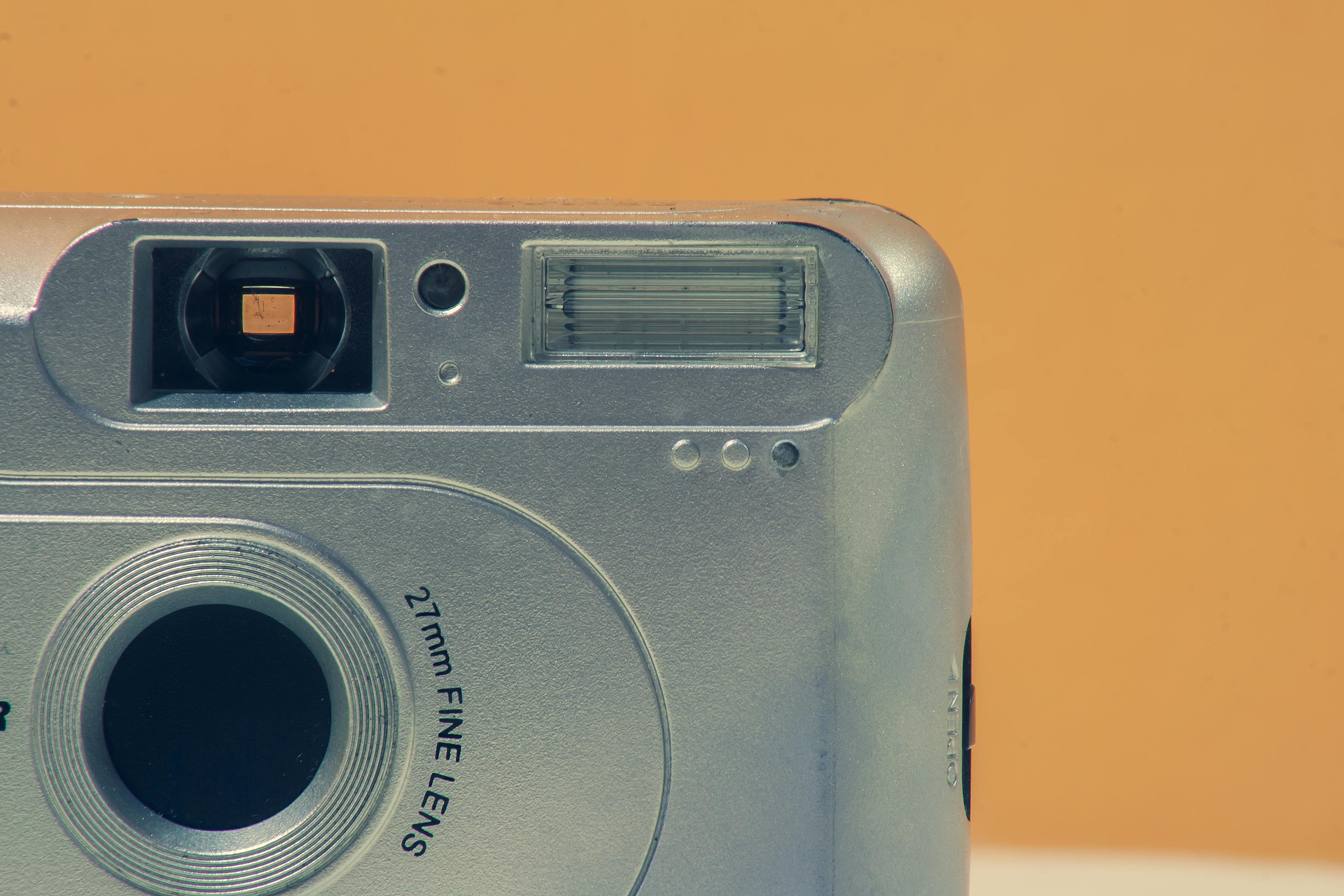 Close-up of a silver vintage camera against a yellow backdrop, showcasing retro tech charm.