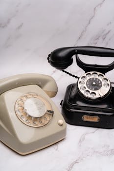 A pair of vintage rotary phones on a marble surface, showcasing classic design.