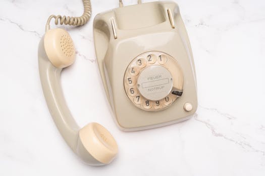 Classic beige rotary telephone on marble, evoking nostalgia and elegance.