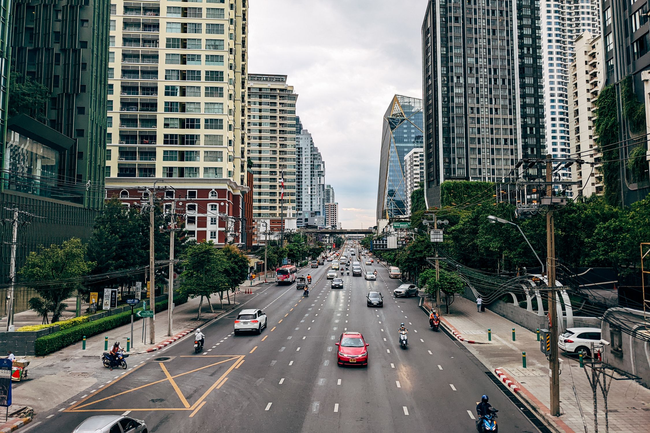 Explore a vibrant Bangkok street lined with modern skyscrapers and active traffic