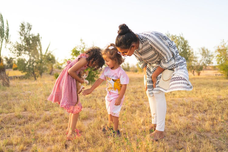 Woman Standing Near Two Girls Holding A Cat