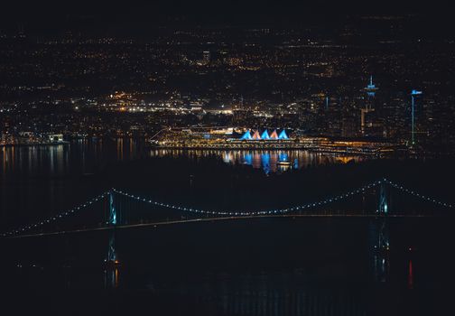 Stunning aerial view of Vancouver's illuminated skyline and bridge at night, showcasing vibrant city lights.