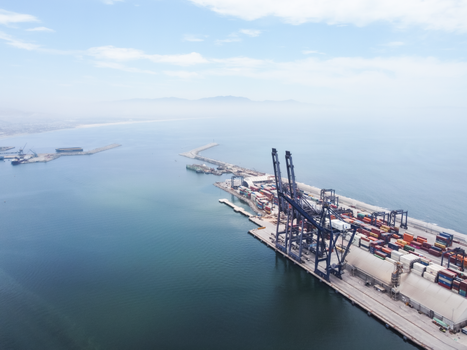 A sweeping aerial shot capturing logistics and container ships at Ensenada Port, Baja California.