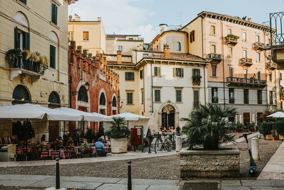 Explore the lively atmosphere of a Verona square filled with sidewalk cafes and historic architecture.