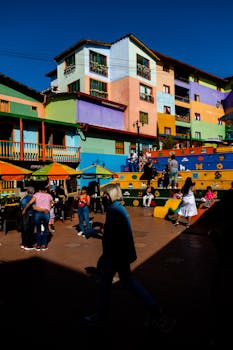 Vibrant urban scene showcasing colorful buildings and people enjoying a sunny day in Guatapé, Colombia.
