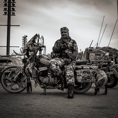 Grayscale Photo of Man Sitting on Motorcycle
