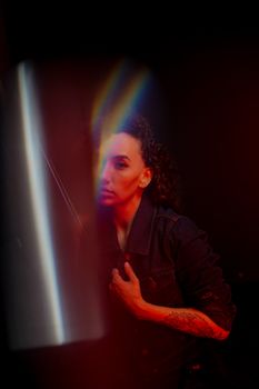 Moody portrait of a woman with tattoos, enhanced by vibrant color spectrum lighting effects.
