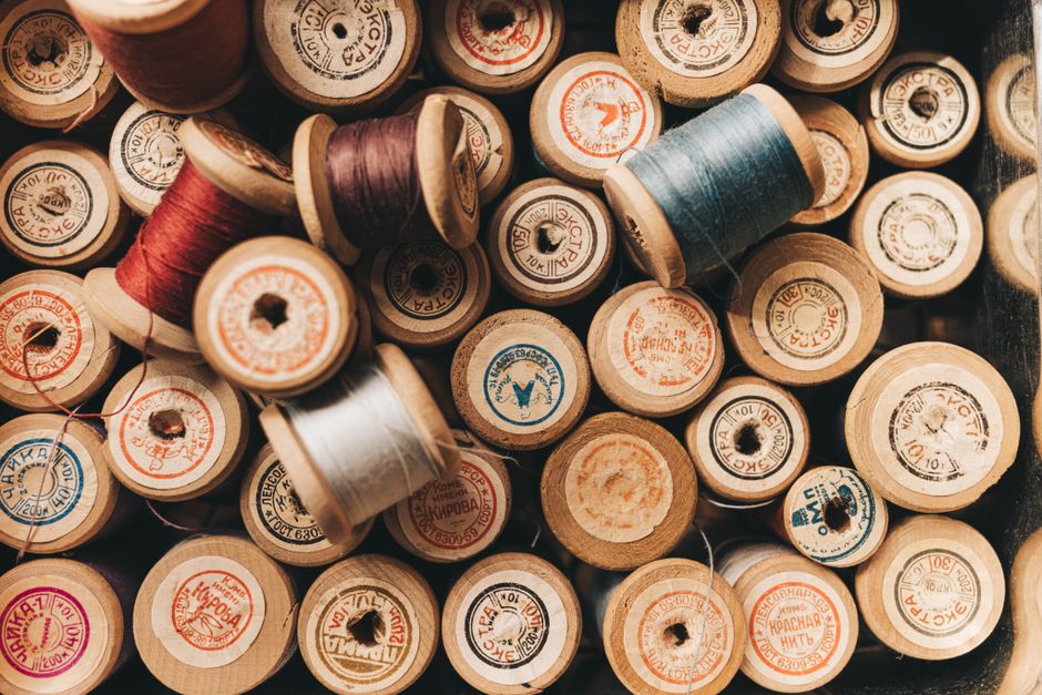 A collection of vintage wooden thread spools with colorful threads, perfect for sewing enthusiasts.