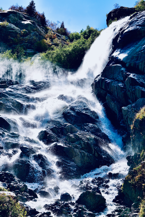 Free Stunning waterfall plunging over rugged cliffs surrounded by lush forest, captured in full daylight. Stock Photo