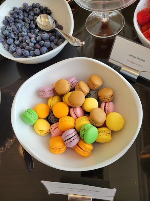 A Colorful French Macarons and Blueberries on a Ceramic Bowls