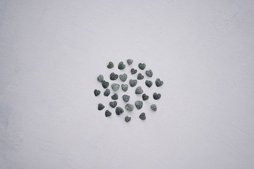Free Minimalist arrangement of heart-shaped pebbles on a light textured surface, offering ample copyspace. Stock Photo