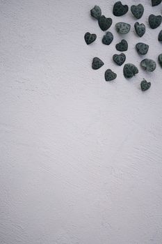 Decorative heart-shaped leaves scattered on a white textured wall, offering ample copy space.