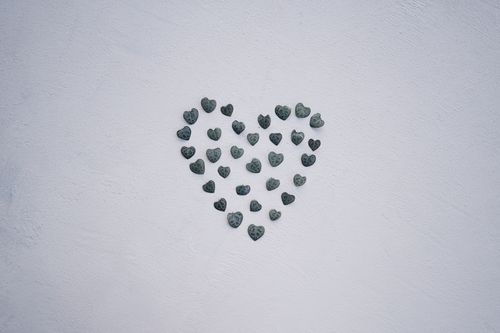 Free Artistic heart shape made of pebbles on a textured white wall, perfect for minimal decor. Stock Photo