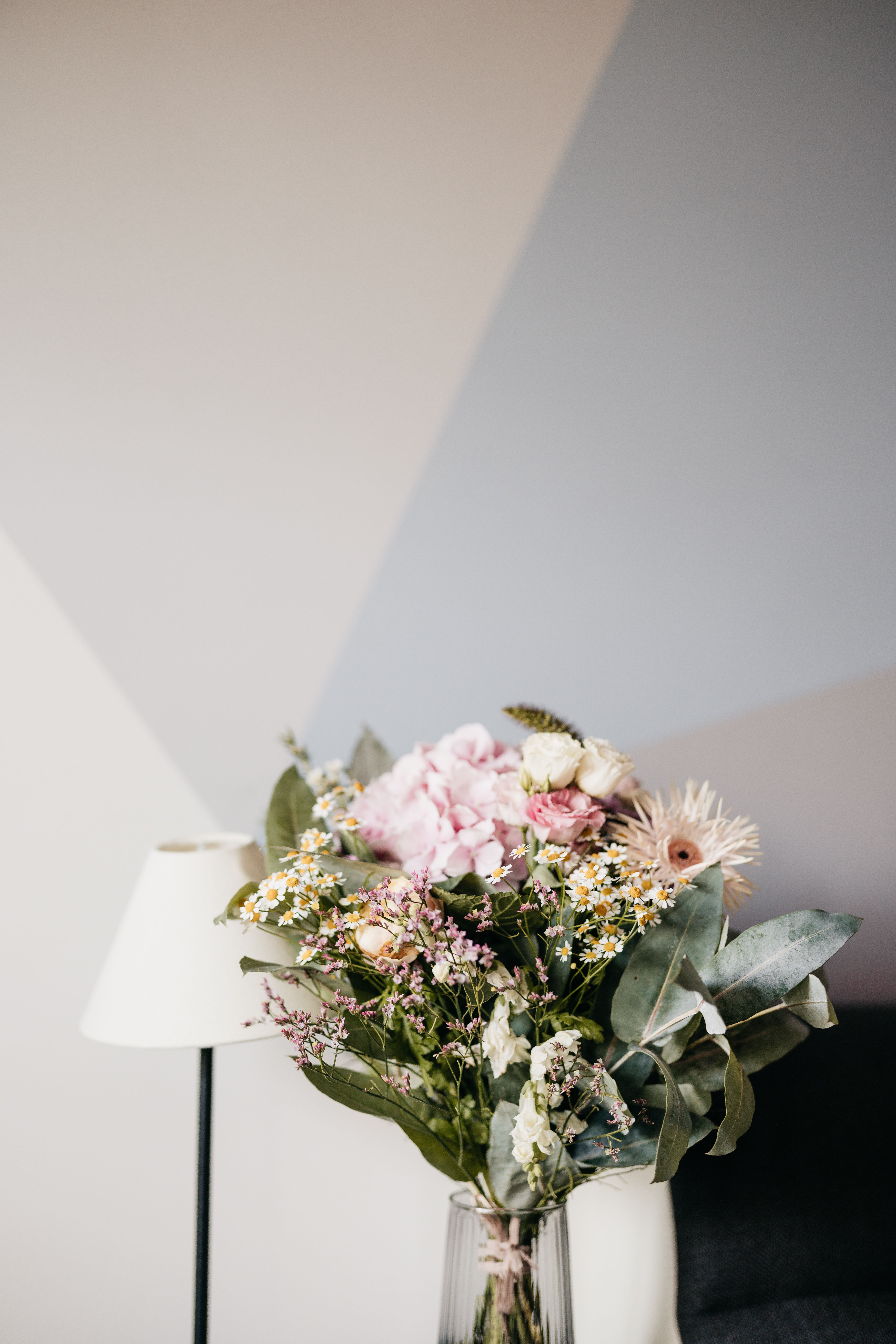 A beautiful floral arrangement in a glass vase against a modern geometric wall background.