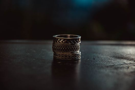 Close-up shot of intricately designed vintage metal rings stacked together on a dark wooden surface.