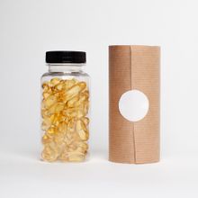 A clear jar of golden capsules beside a plain kraft carton. Photo by Supplements On Demand on Pexels.