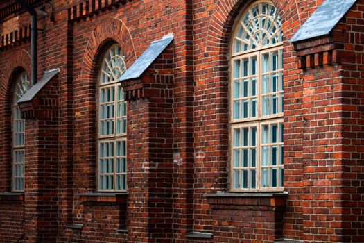 Detailed view of a historic brick building facade with arched windows, showcasing architectural design.