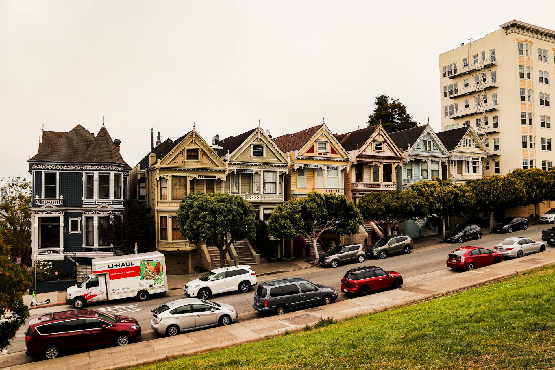 Historic Painted Ladies homes with parked cars in San Francisco, showcasing Victorian architecture.