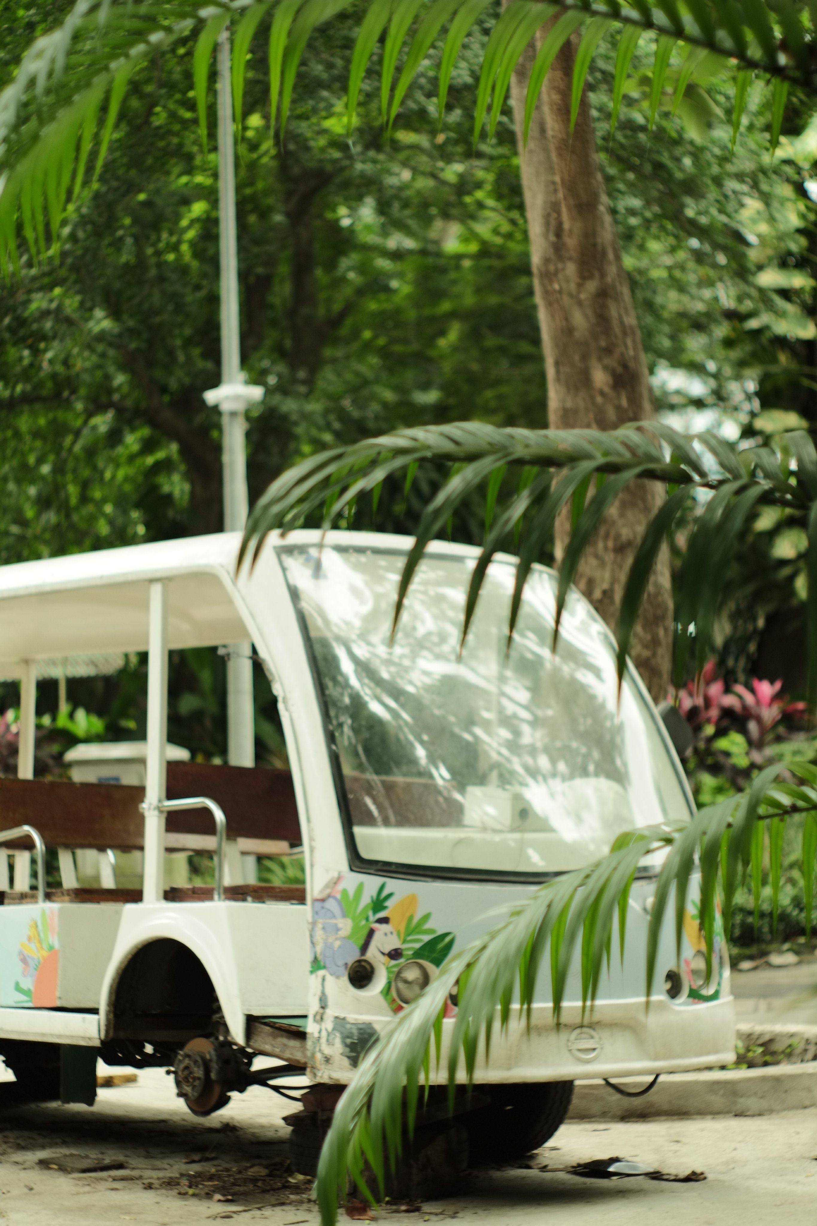 An abandoned decorative bus parked amidst lush greenery, covered in floral patterns.