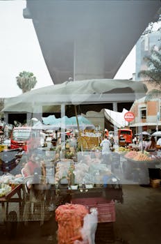 Reflection of a bustling street market in Medellín, highlighting local culture and commerce.
