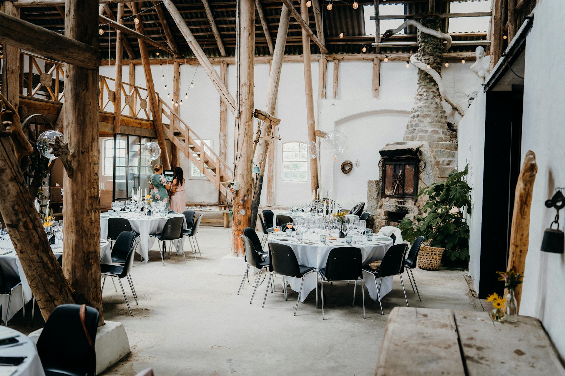 Charming rustic barn interior with elegantly set tables and ambient lighting, perfect for events.