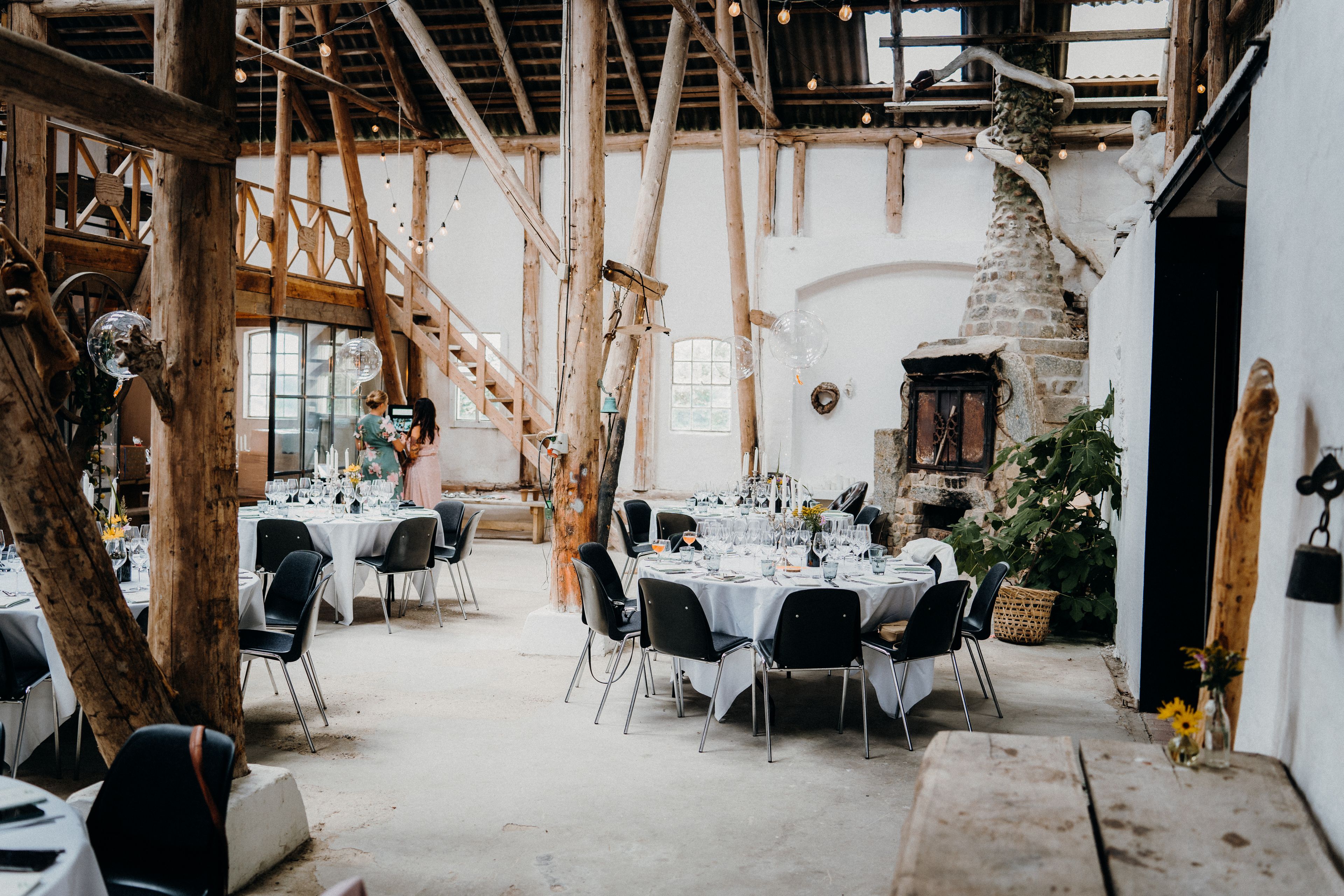 A converted barn set with round tables before an event