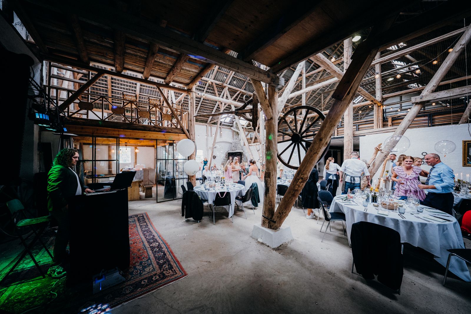 Wedding reception with guests and a DJ in a rustic event space