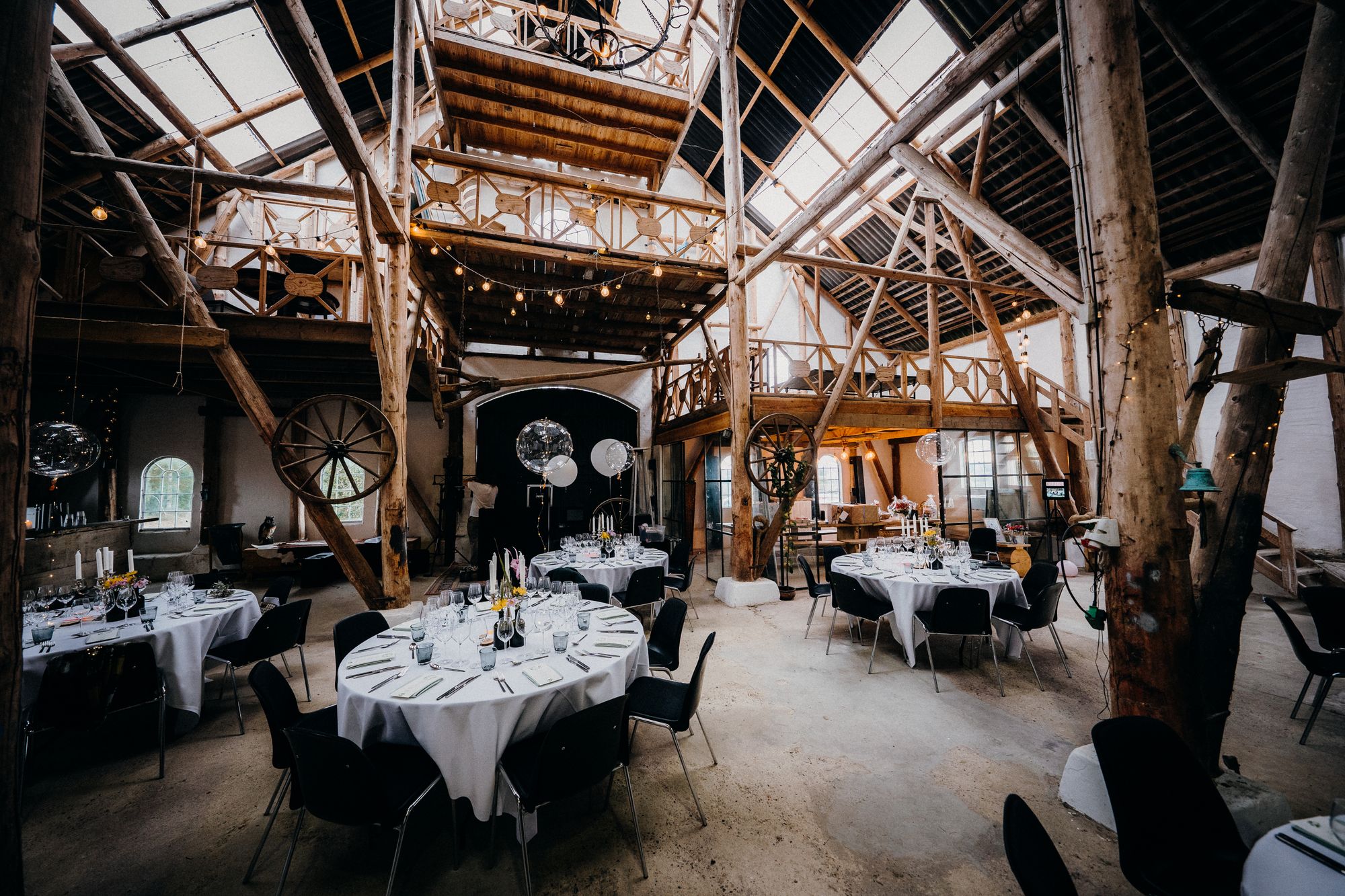 The barn laid for dinner with round tables